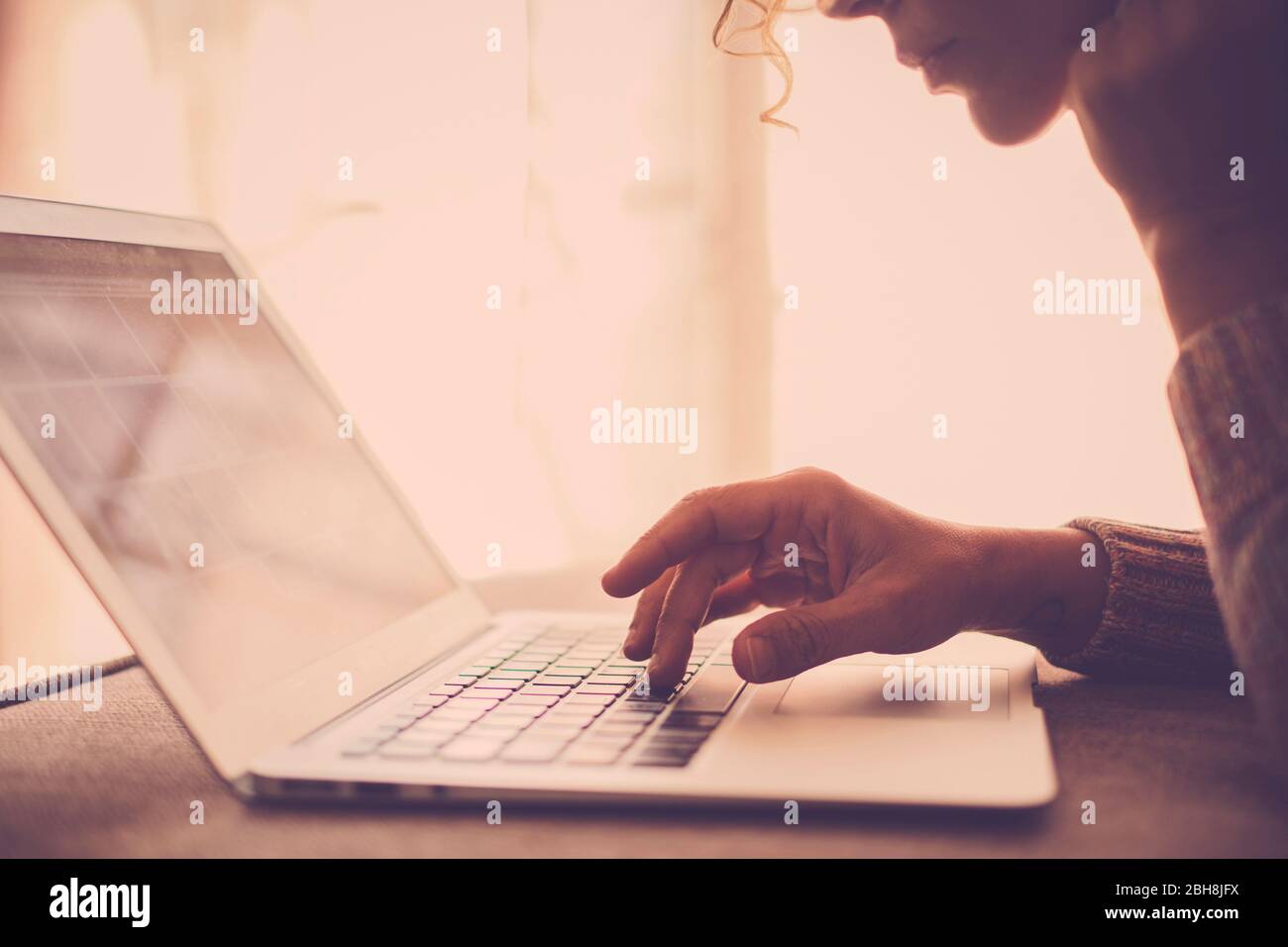 donna con capelli ricci e occhiali che lavora con computer portatile comodamente seduto sul divano a casa. Concetto di indipendenza tecnologica fuori sede per uno stile di vita libero alternativo per i moderni nomadi digitali Foto Stock
