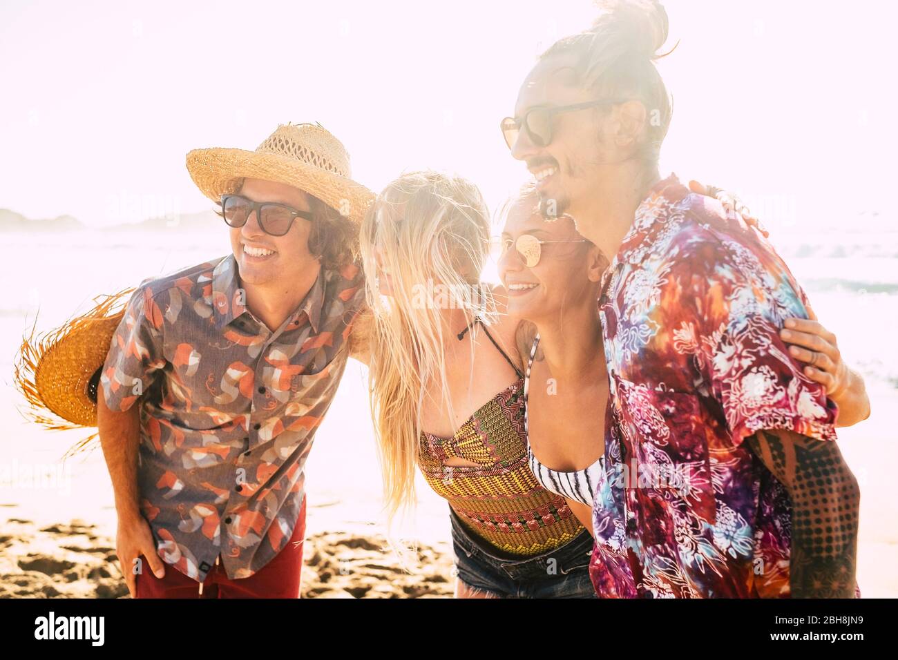 Gruppo di amici carini persone abbracciare insieme e posa per una foto sorridente - allegro grazioso ragazze e ragazzi giovane concetto per vacanze estive in spiaggia - sole luminoso in retroilluminazione - amicizia e rapporto Foto Stock