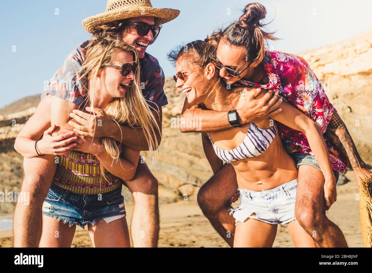 Allegro gruppo felice di persone amici ridono molto all'aperto alla spiaggia - estate viaggio concetto di vacanza con donne che trasportano uomini - sole e divertente stile di vita per alternative millennial - bellissimo resort Foto Stock