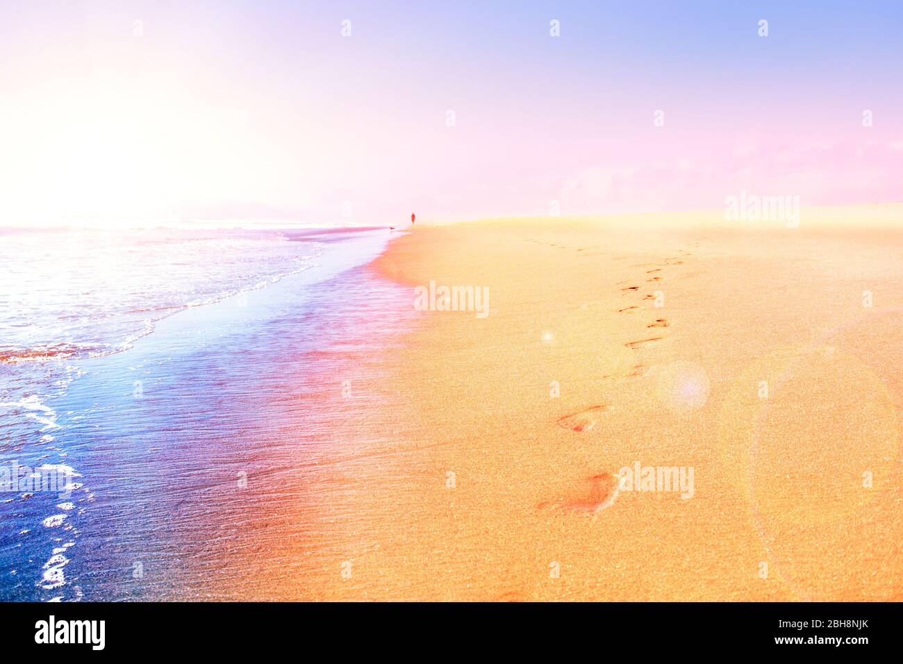 Impronte sulla sabbia vicino alle onde del mare al tramonto Foto Stock