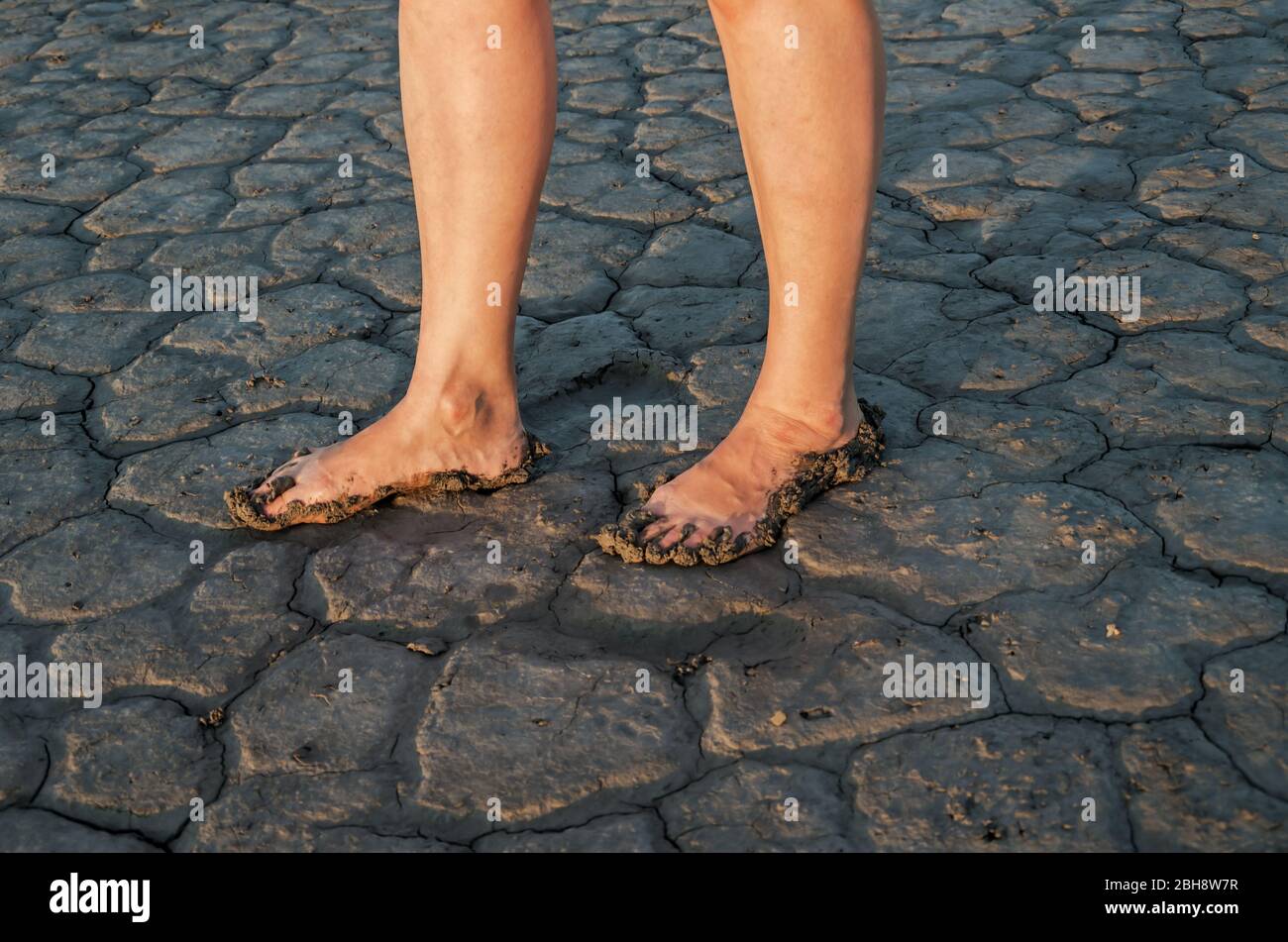 Gambe di donna matura in sporco che si trova sul fondo asciutto di estuario salato Foto Stock