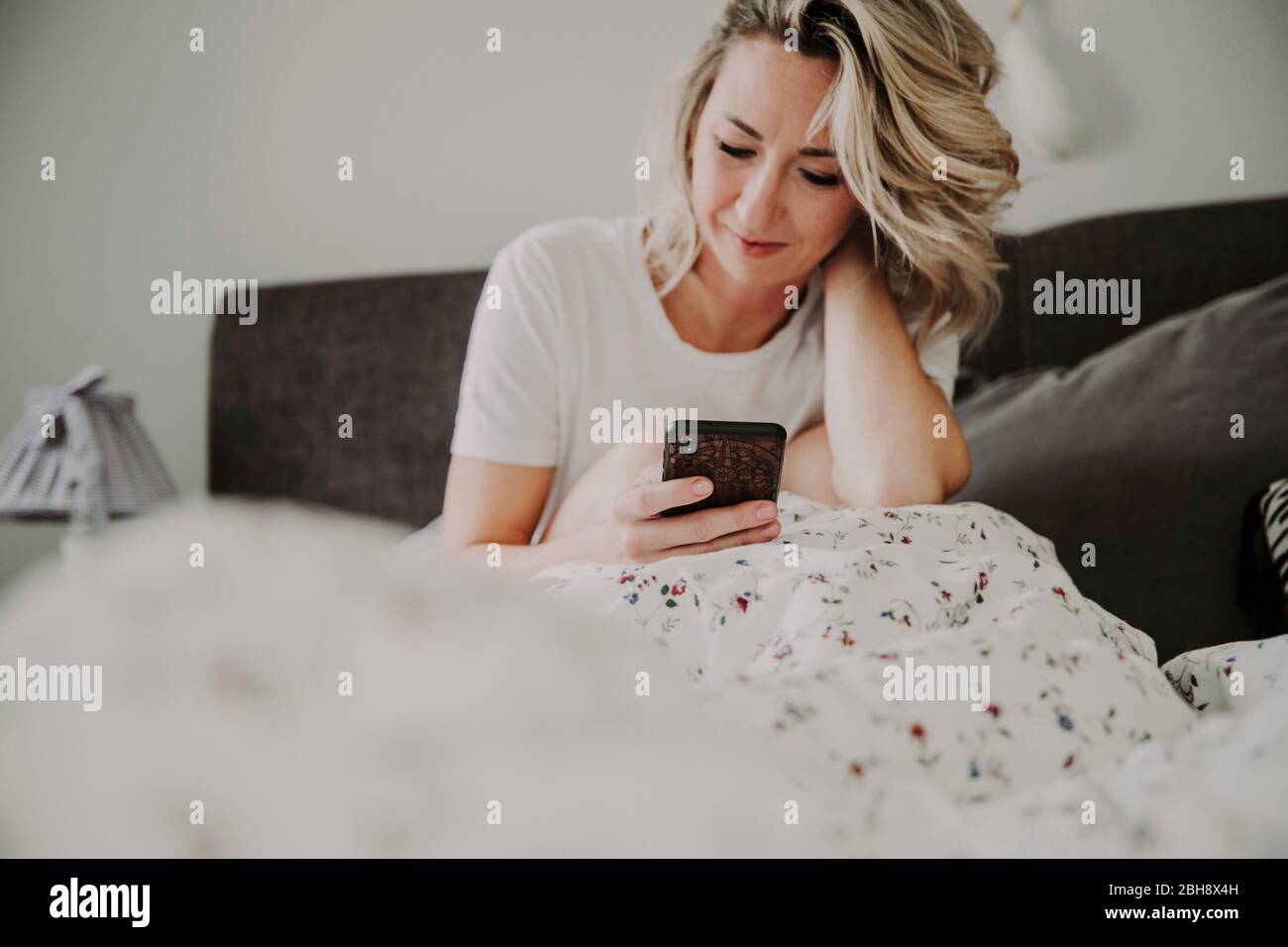 Frau mit smartphone im Bett Foto Stock
