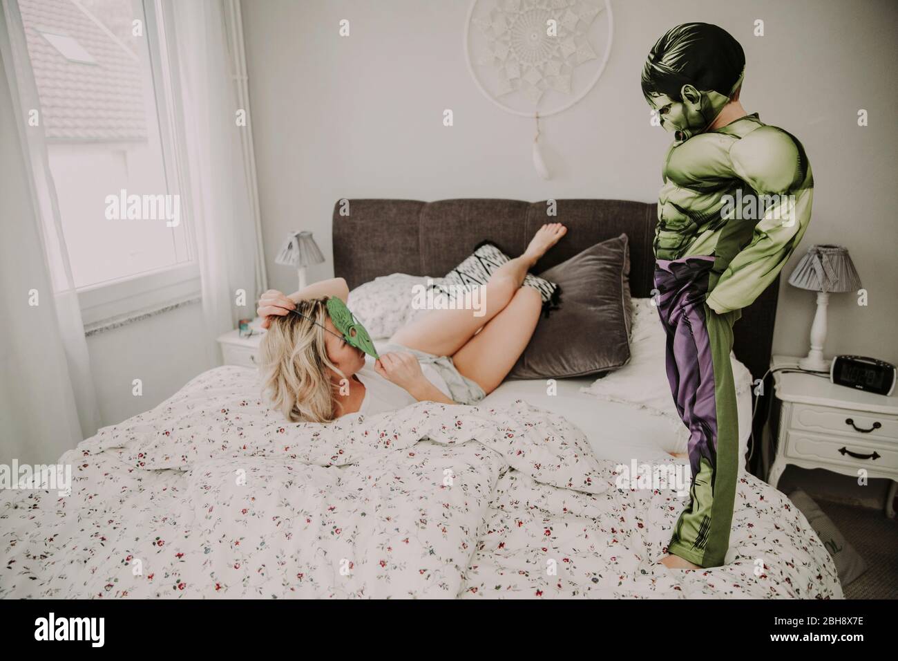 Mutter und Sohn im Bett, Spaß, erumalbern, Kostüm, Maske Foto Stock