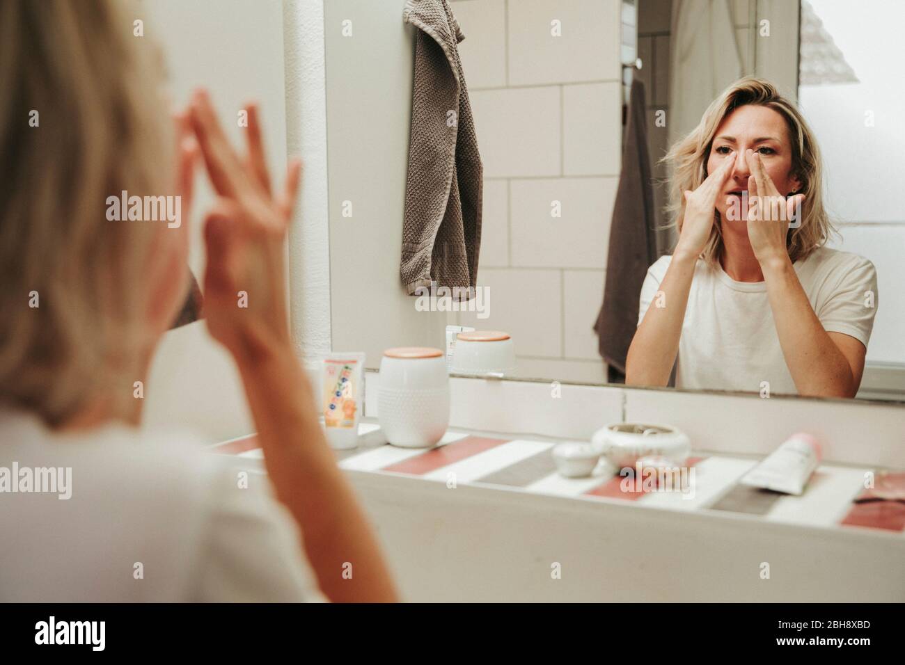 Frau im Badezimmer, cremt ihr Gesicht ein Foto Stock