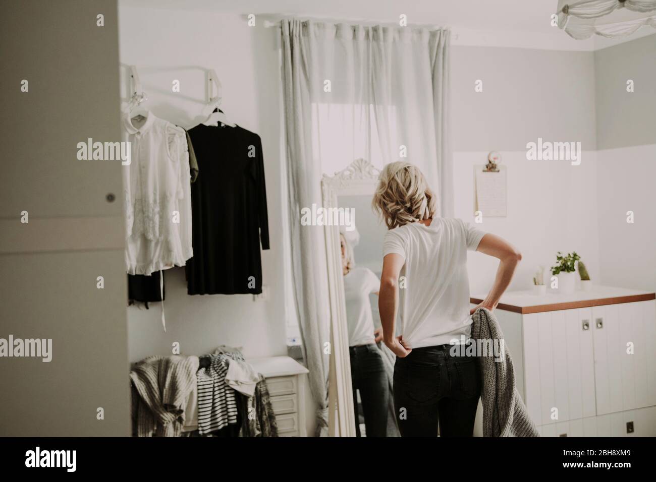 Frau steht vor dem Spiegel, kleidet sich an Foto Stock