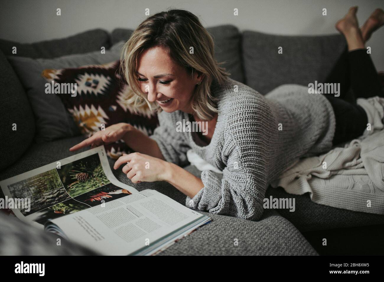Frau mit Zeitschrift auf der Couch Foto Stock