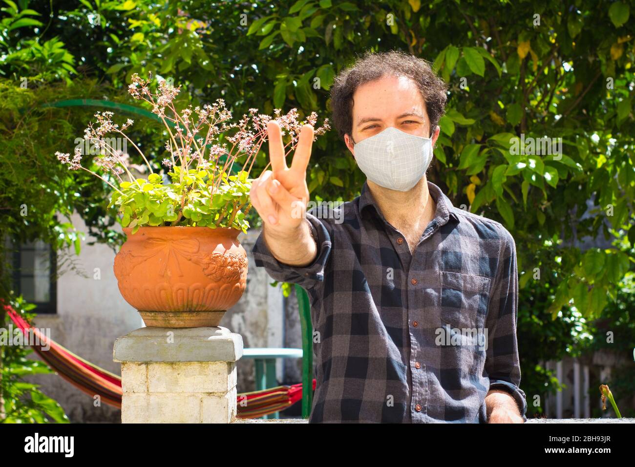 Giovane uomo con maschera di prevenzione facendo segno di vittoria Foto Stock