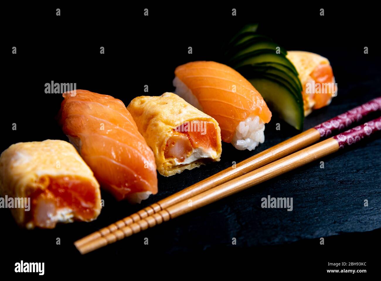 Cucina giapponese nigiri sushi set su piatto nero servito con wasabi, salsa di soia. Sushi Roll con salmone, sushi maki roll e tamago sushi su pla nero Foto Stock