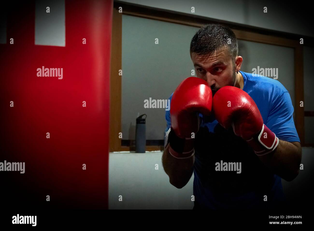 Vista laterale di un pugile uomo sicuro che si esercita in palestra Foto Stock