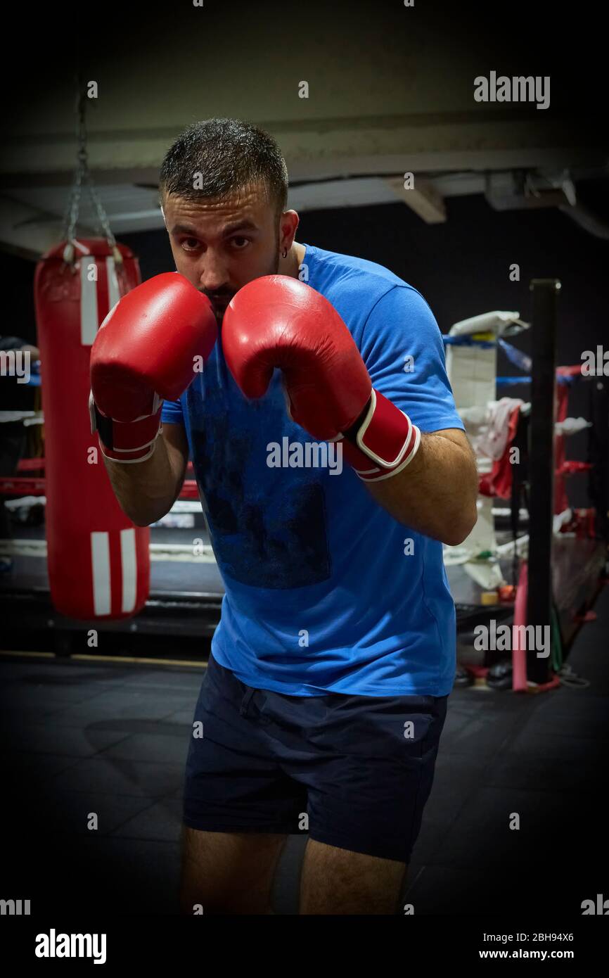 Vista laterale di un pugile uomo sicuro che si esercita in palestra Foto Stock