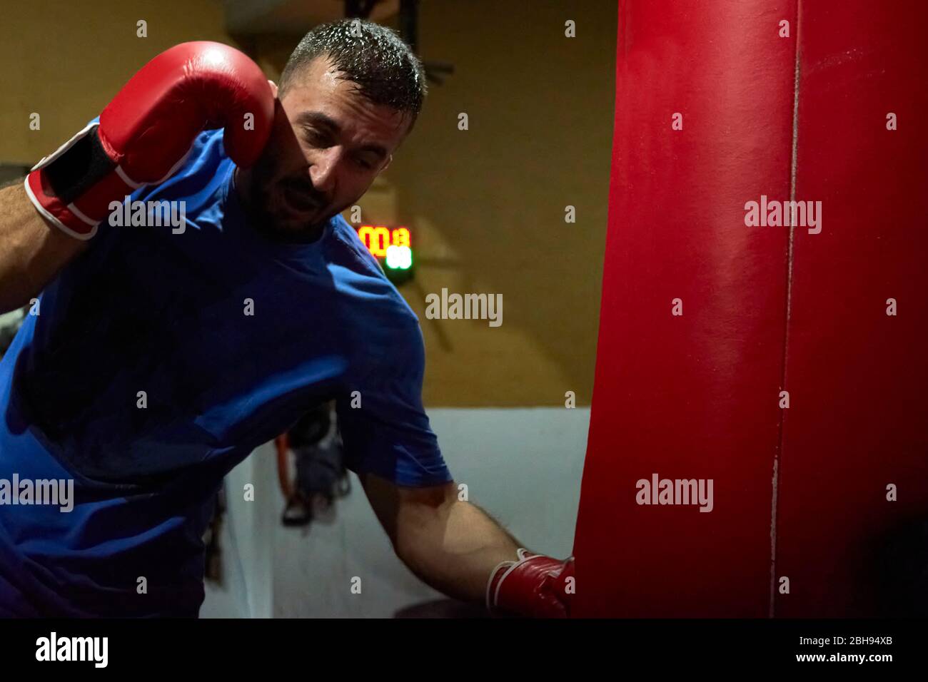 Vista laterale di un pugile uomo sicuro che si esercita in palestra Foto Stock
