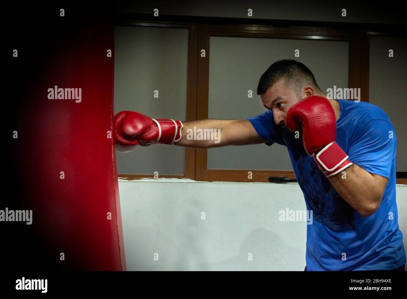 Vista laterale di un pugile uomo sicuro che si esercita in palestra Foto Stock
