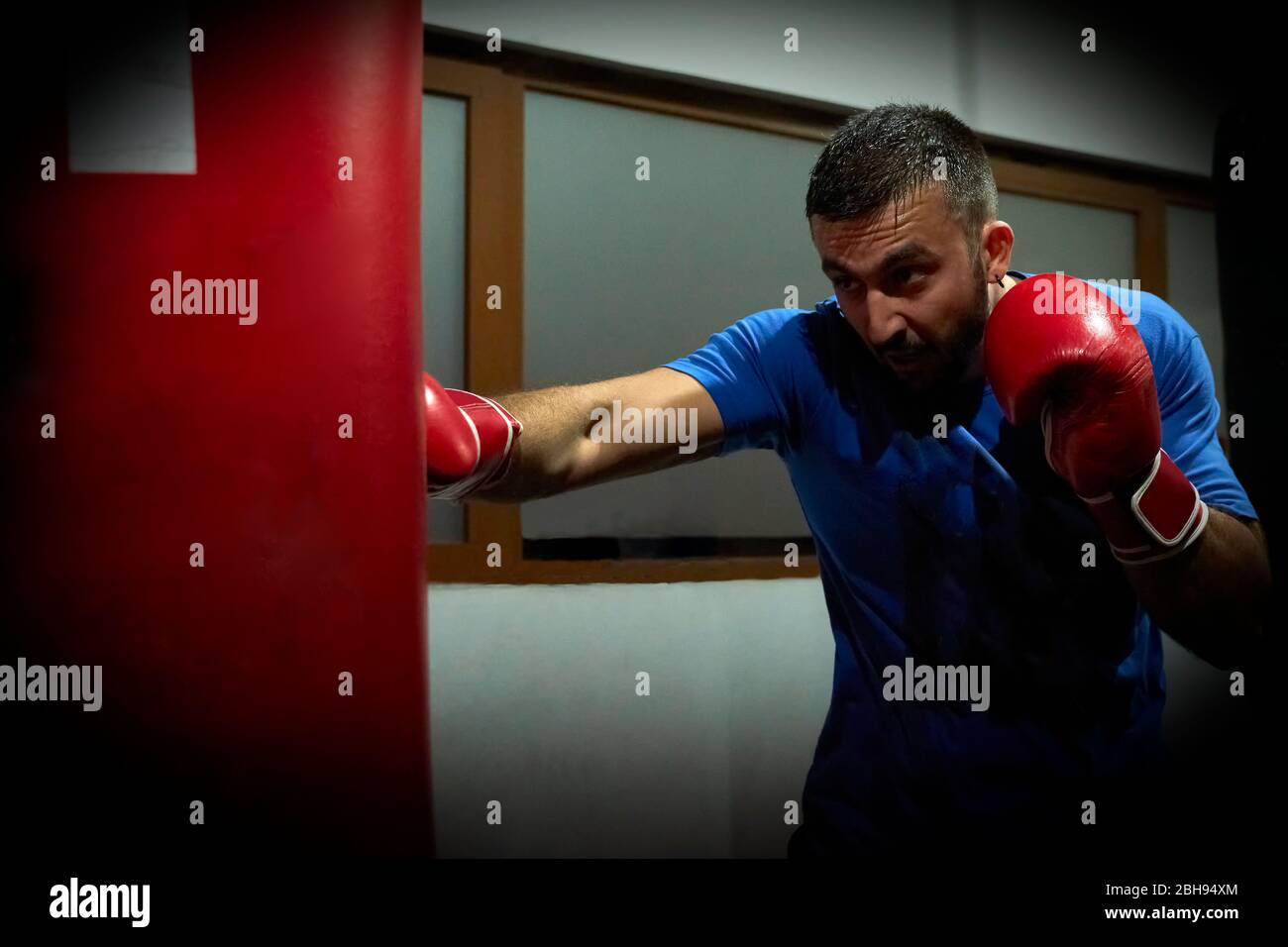 Vista laterale di un pugile uomo sicuro che si esercita in palestra Foto Stock