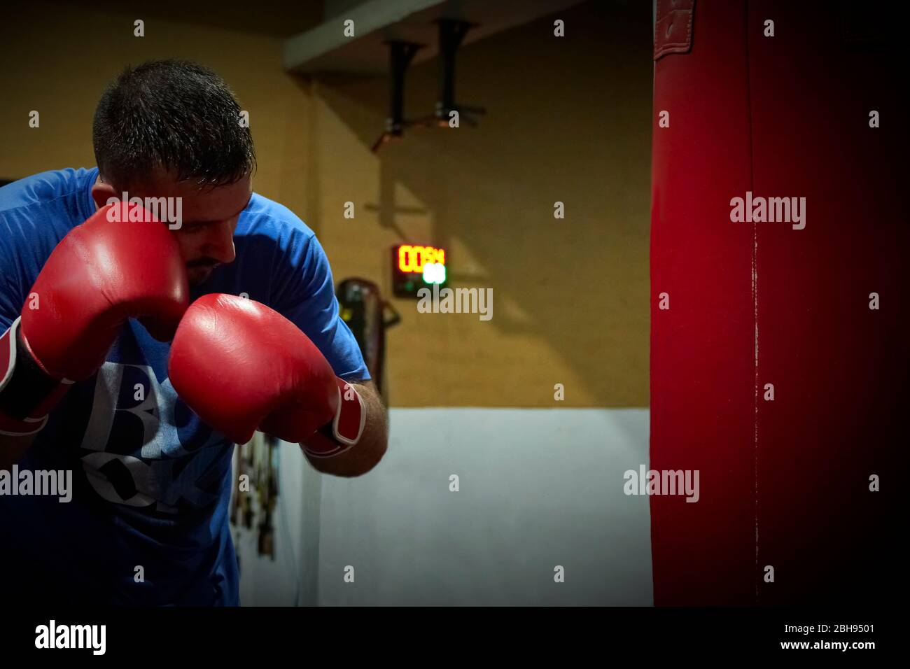 Vista laterale di un pugile uomo sicuro che si esercita in palestra Foto Stock