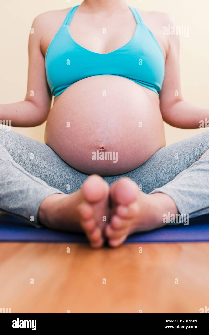 Donna asiatica incinta rilassante mentre fa il suo Yoga esercizio Foto Stock