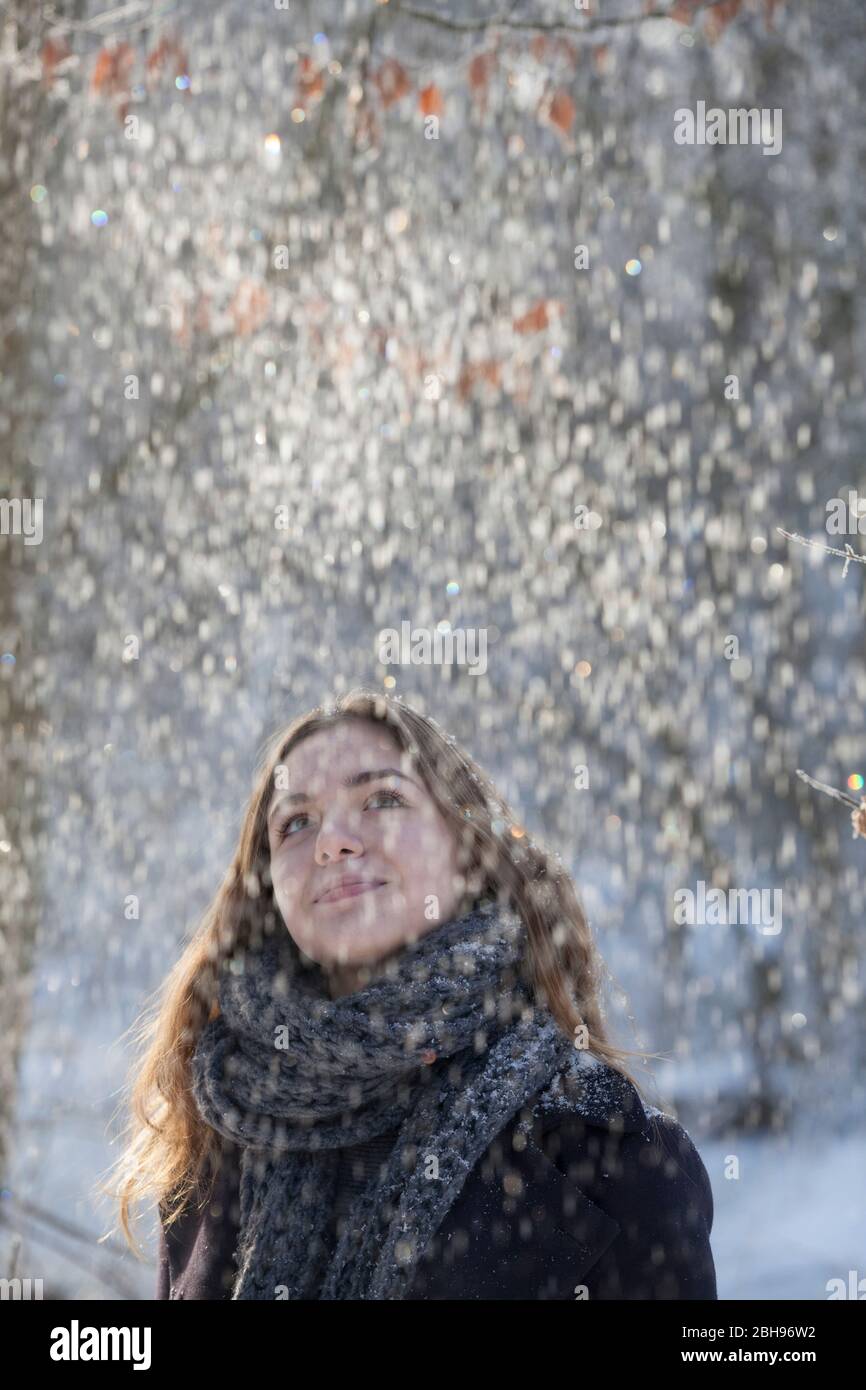 Giovane donna guarda giù alla neve che cade Foto Stock