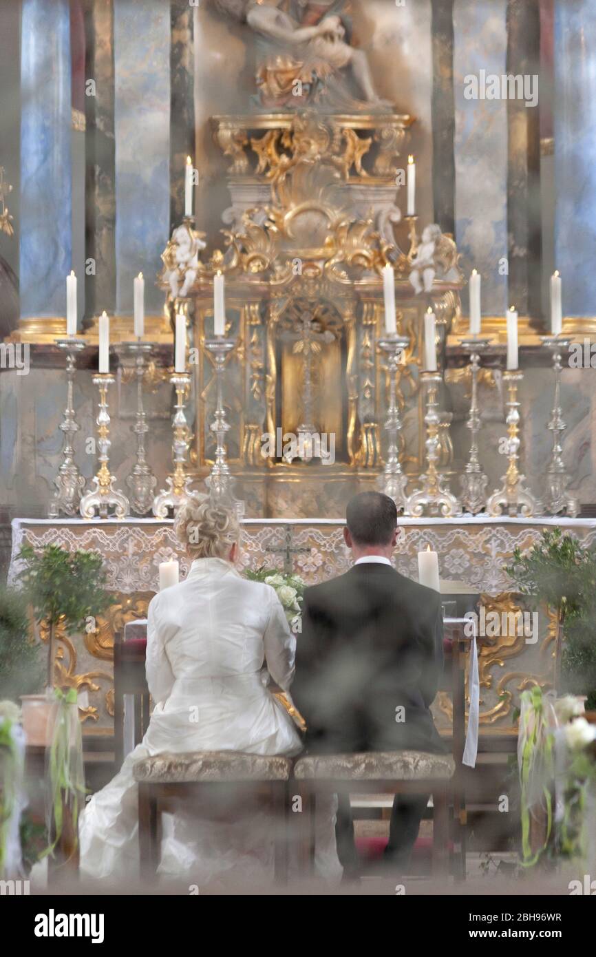Vista attraverso il reticolo della porta sulla coppia nuziale in chiesa, coppia nuziale ombra da dietro Foto Stock