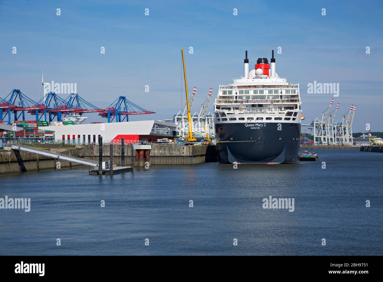 La Regina Maria 2 della compagnia di navigazione Cunard presso il terminal delle navi da crociera Steinwerder. Dietro di esso i ponti container del terminale Tollerort. Foto Stock