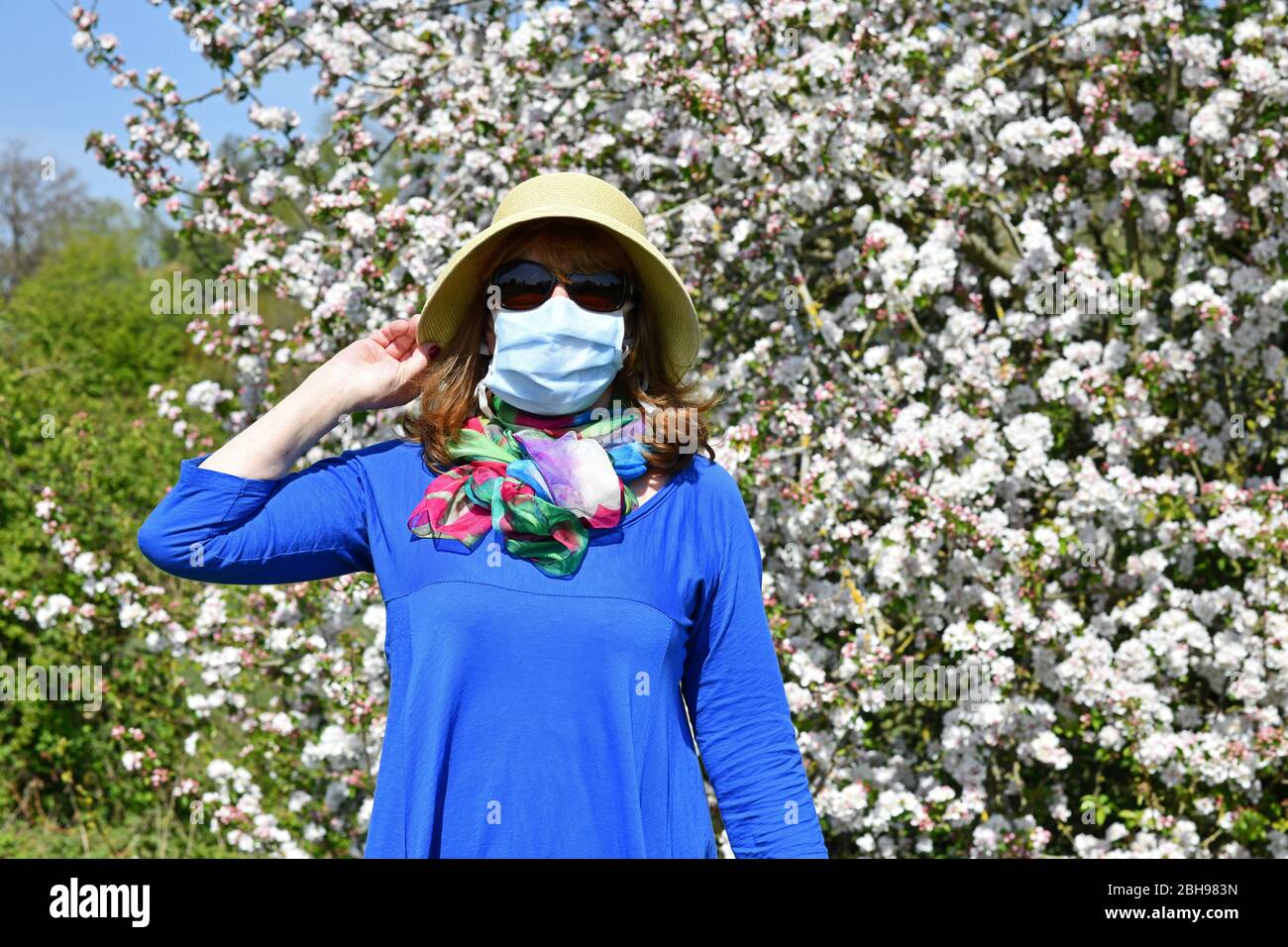 Donna che indossa la maschera facciale durante la pandemia di Coronavirus Gran Bretagna in fiore 2020. Maschera facciale COVID 19 coronavirus Foto Stock
