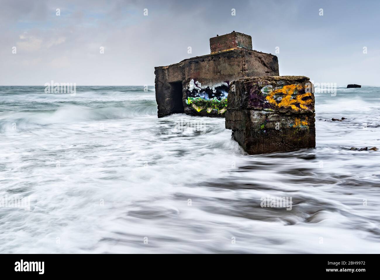 Germania, Meclemburgo-Pomerania occidentale, penisola Fischland-Darß-Zingst, località balneare Wustrow, Parco Nazionale Vorpommersche Boddenlandschaft, Hohes Ufer (alta riva), vecchi bunker con graffiti nel surf del Mar Baltico sotto le scogliere a tempesta Foto Stock