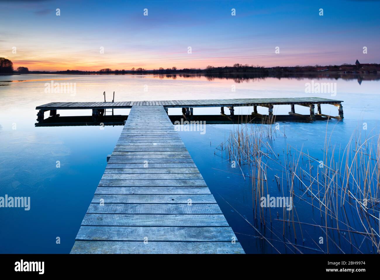 Tramonto sul lago di Krakower in inverno, passeggiata sul lungomare, ghiaccio sull'acqua, Mecklenburg-Vorpommern, Germania Foto Stock