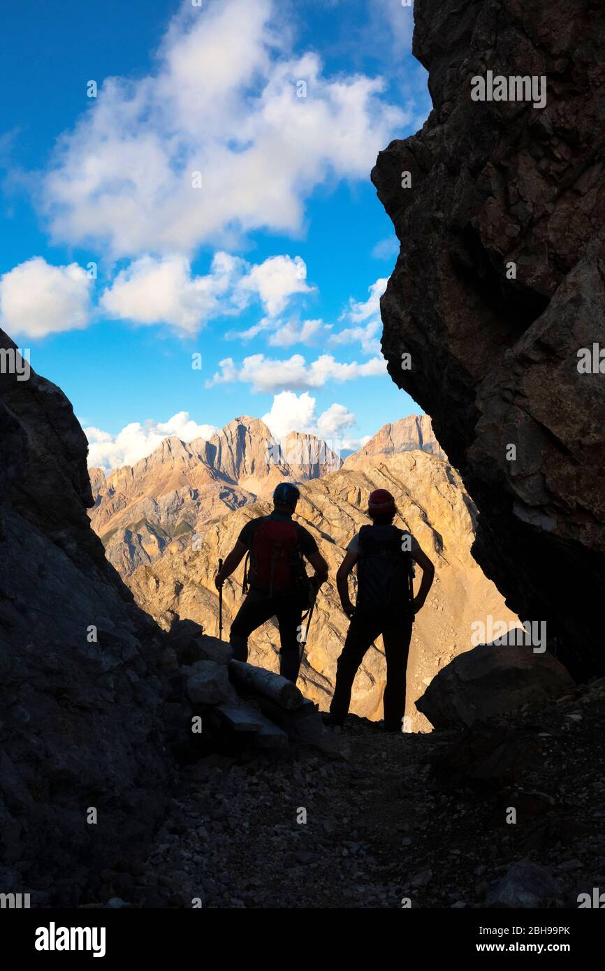 Due escursionisti che guardano il gruppo del Gran Vernel in una piccola forcella lungo l'Alto sentiero Bepi Zac, il crinale Costabella, il gruppo Marmolada, le Dolomiti, la Val di Fassa, la provincia di Trento, il Trentino-Alto Adige, Italia Foto Stock