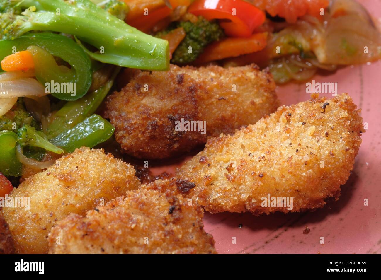 Pepite di pollo fritte e insalata sul piatto. Foto Stock