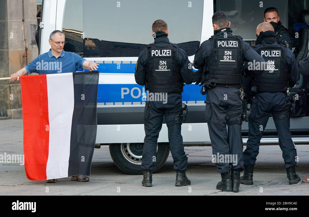 Chemnitz, Germania. 24 Aprile 2020. Un uomo lancia la bandiera della Confederazione tedesca del Nord e del Reich tedesco accanto ai poliziotti dopo l'identificazione personale. I membri dell'associazione estremista di destra Pro Chemnitz avevano pianificato un raduno al monumento Karl Marx. Dopo che la manifestazione era stata vietata dalla Corte amministrativa superiore della Sassonia, la polizia ha sciolto gruppi di manifestanti da Pro Chemnitz. Credit: Peter Endig/dpa-Zentralbild/dpa/Alamy Live News Foto Stock