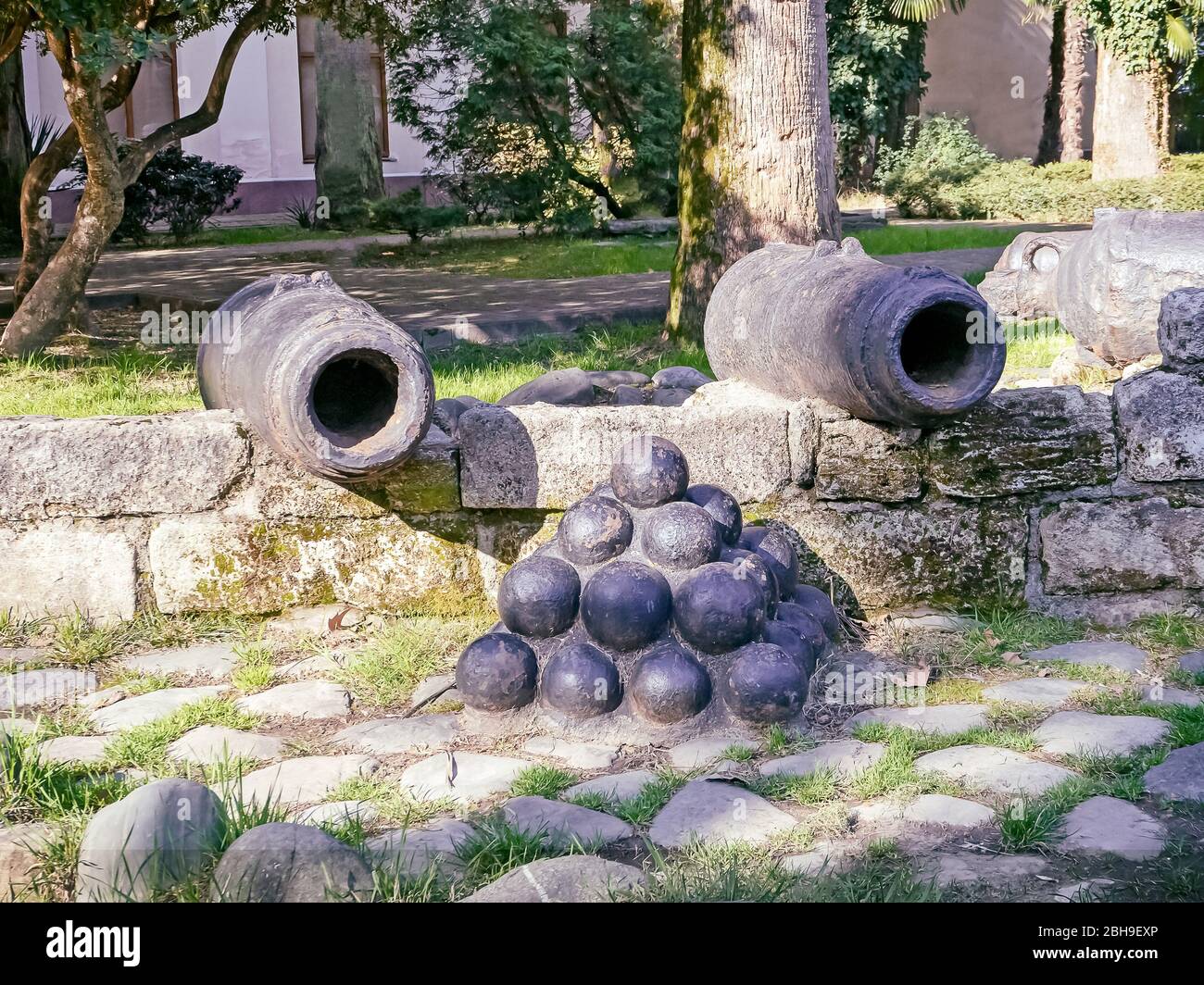 Palloni neri e due vecchi cannoni dietro la recinzione Foto Stock