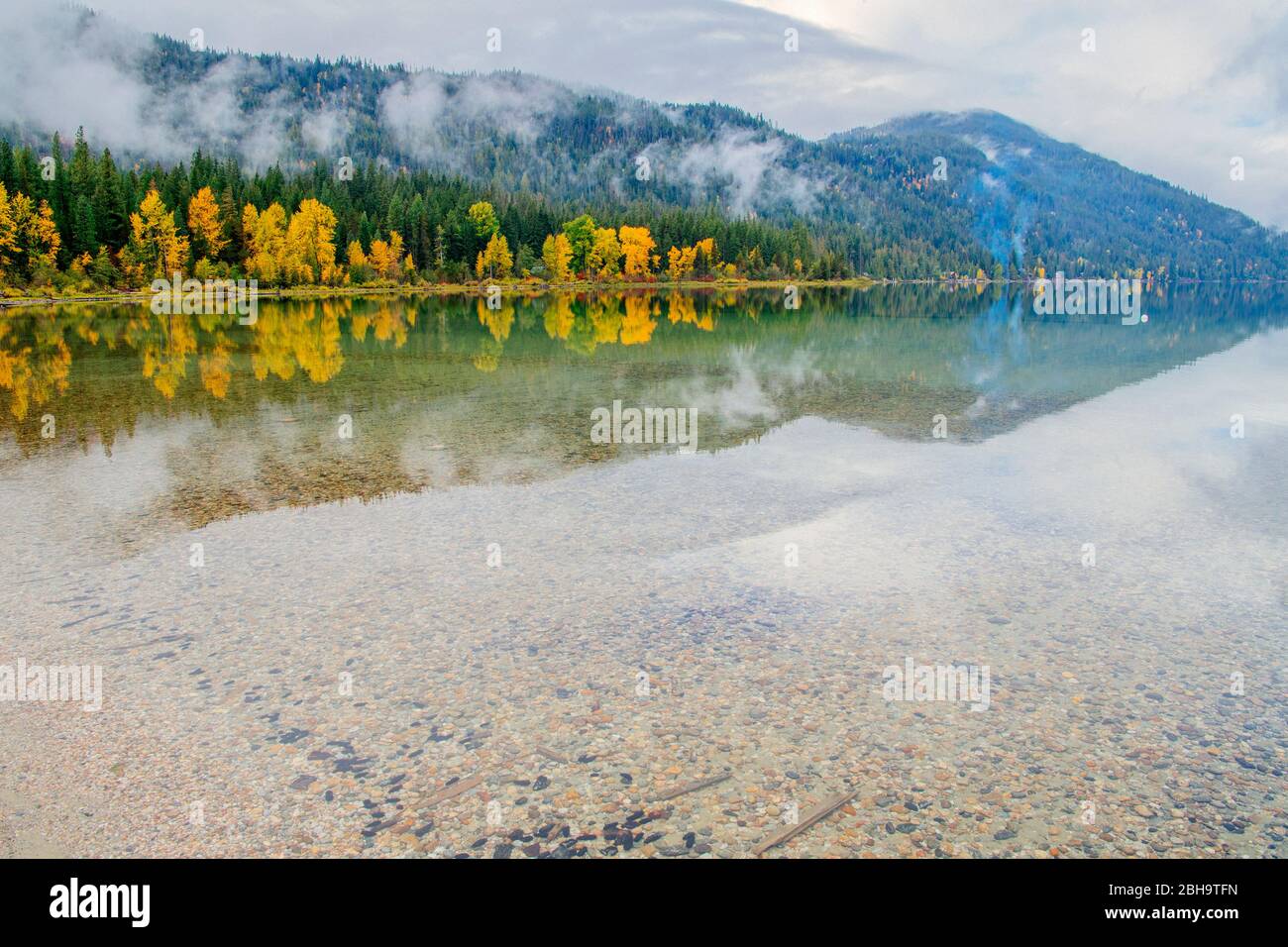 Vista della riflessione in un lago roccioso di foresta e collina ricoperta di nuvole, Lake Wenatchee state Park, Wenatchee, Washington, USA Foto Stock