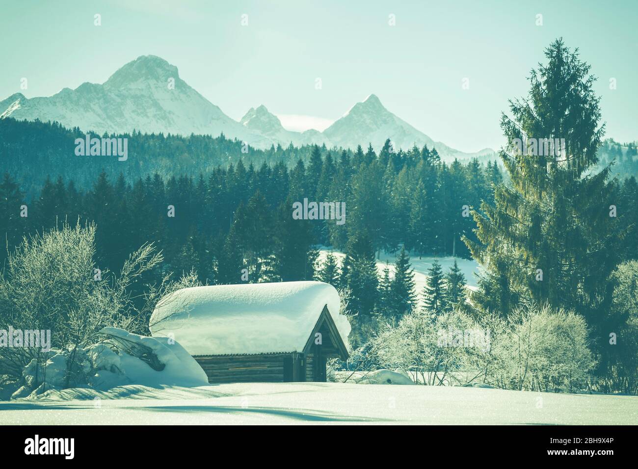 Una capanna innevata a Tennsee vicino a Krün in inverno con vista sul massiccio del Wetterstein e sulle cime delle Alpi a Landkreis Garmisch-Partenkirchen, Baviera, Germania. Foto Stock