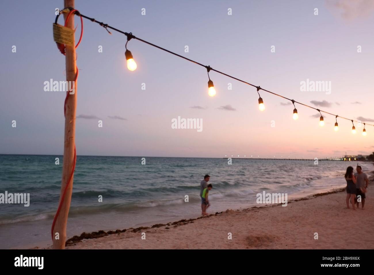 La spiaggia caraibica a Playa del Carmen, Messico, è illuminata da una linea elettrica di fortuna con lampadine Foto Stock