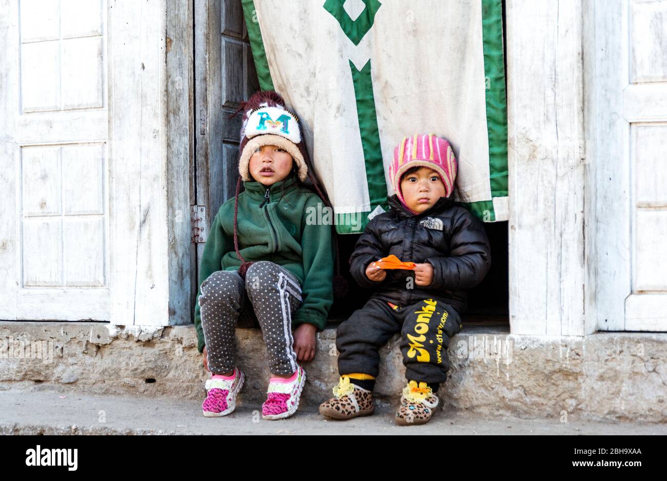 2 bambini piccoli seduti di fronte all'ingresso della casa, 3-6 anni, ritratto Foto Stock