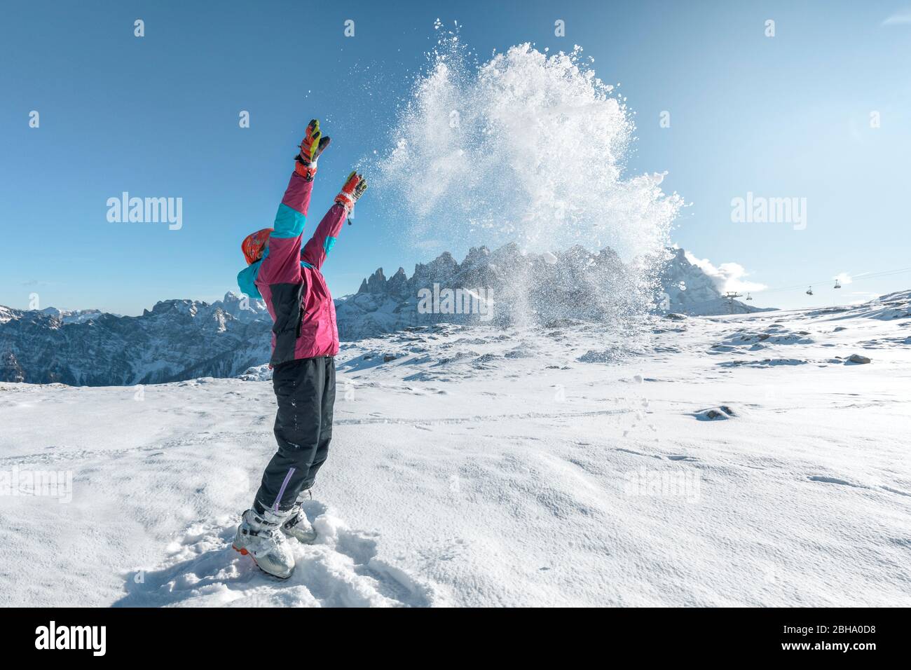 9 anni di età gioca a gettare la neve in aria nella capanna Laresei, di fronte alle pale di San Martino, Falcade, Dolomiti, Belluno, Veneto, Italia Foto Stock