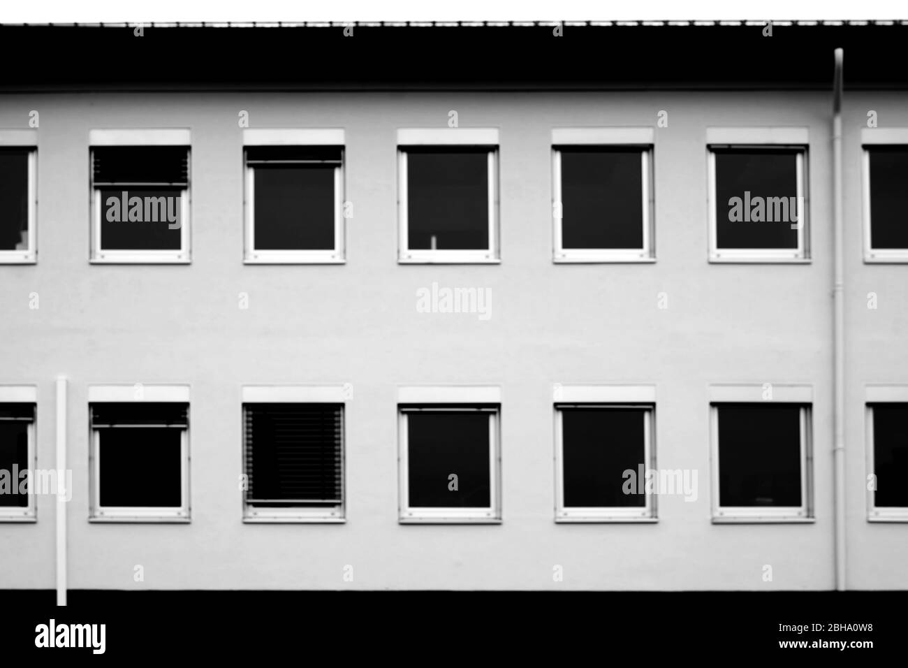 Le semplici finestre di un edificio per uffici con persiane di nero. Foto Stock