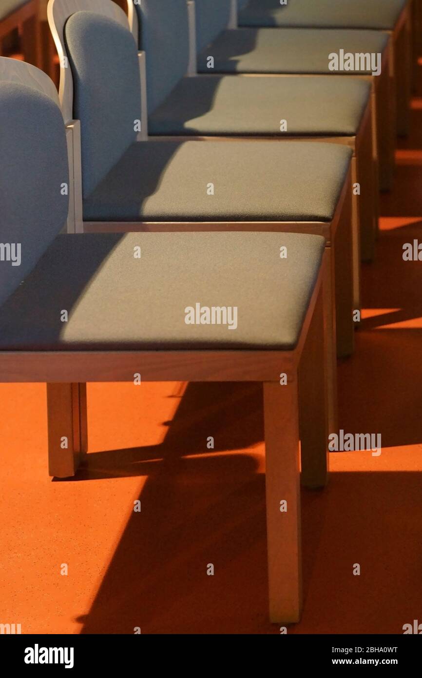 Una riga vuota di sedi con moderne sedie quadrati getta ombre. Foto Stock