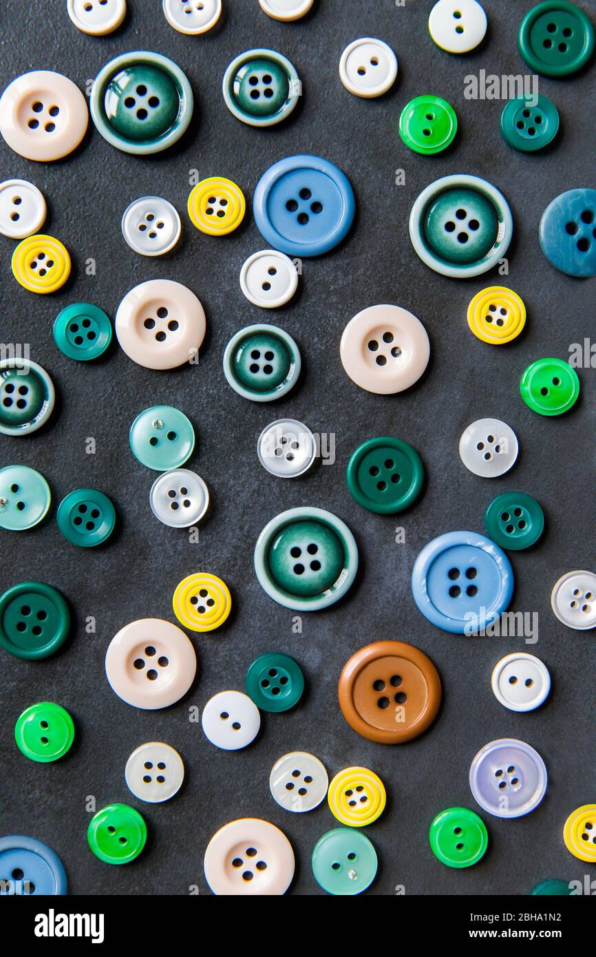 Bottoni colorati misti su sfondo nero, piatto. Vista dall'alto. Foto Stock