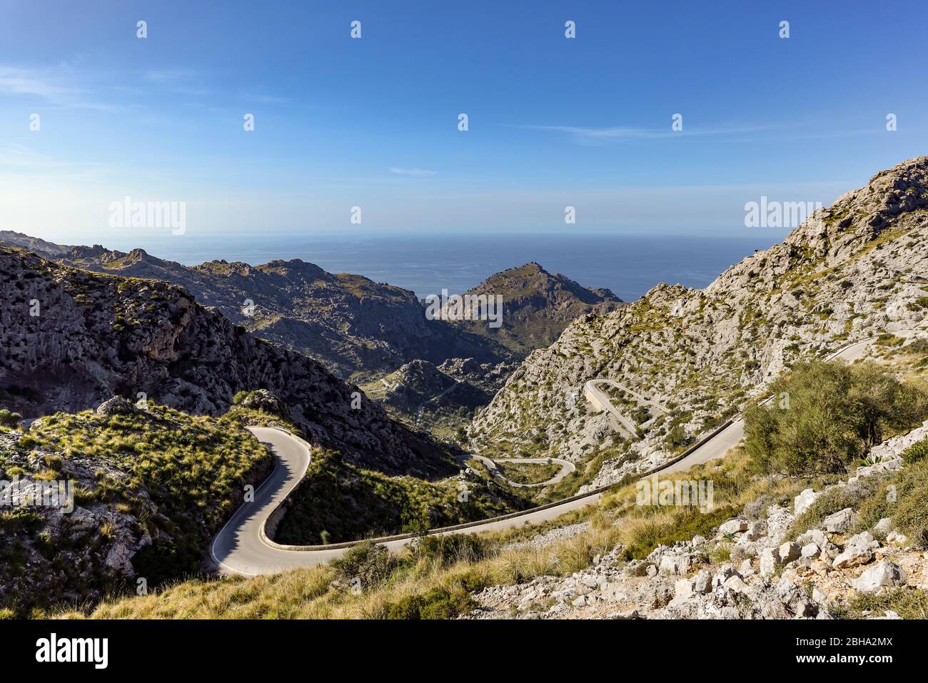 Vista della strada a serpentina con le sue numerose curve sulle montagne rocciose della Tramuntana a Maiorca dall'alto, sullo sfondo il mare Mediterraneo Foto Stock