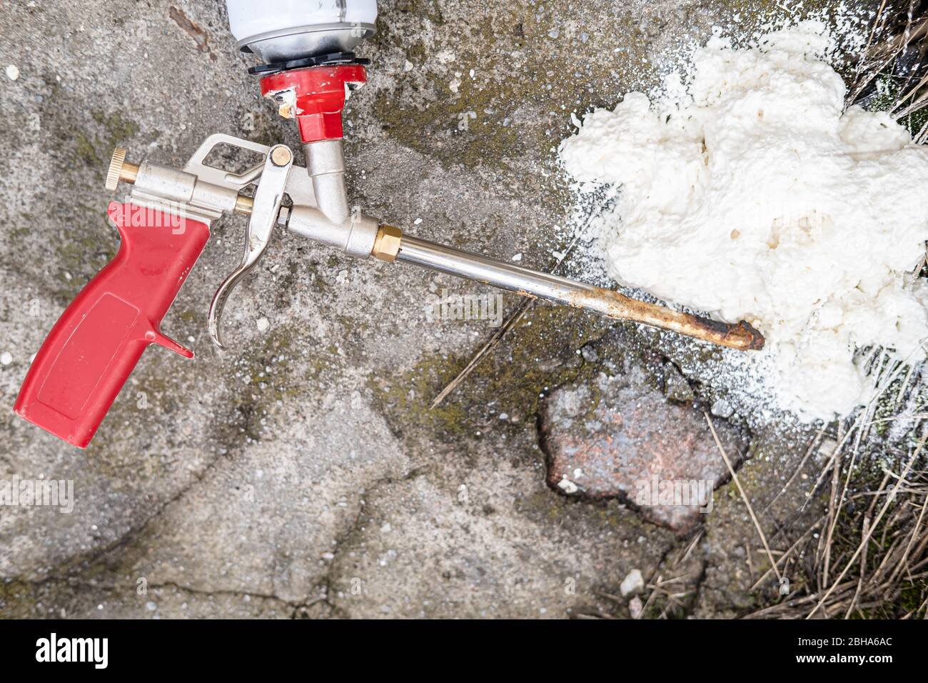 Pistola spray professionale rotta per schiuma isolante con palloncino su pavimento in cemento. Vista dall'alto. Foto Stock