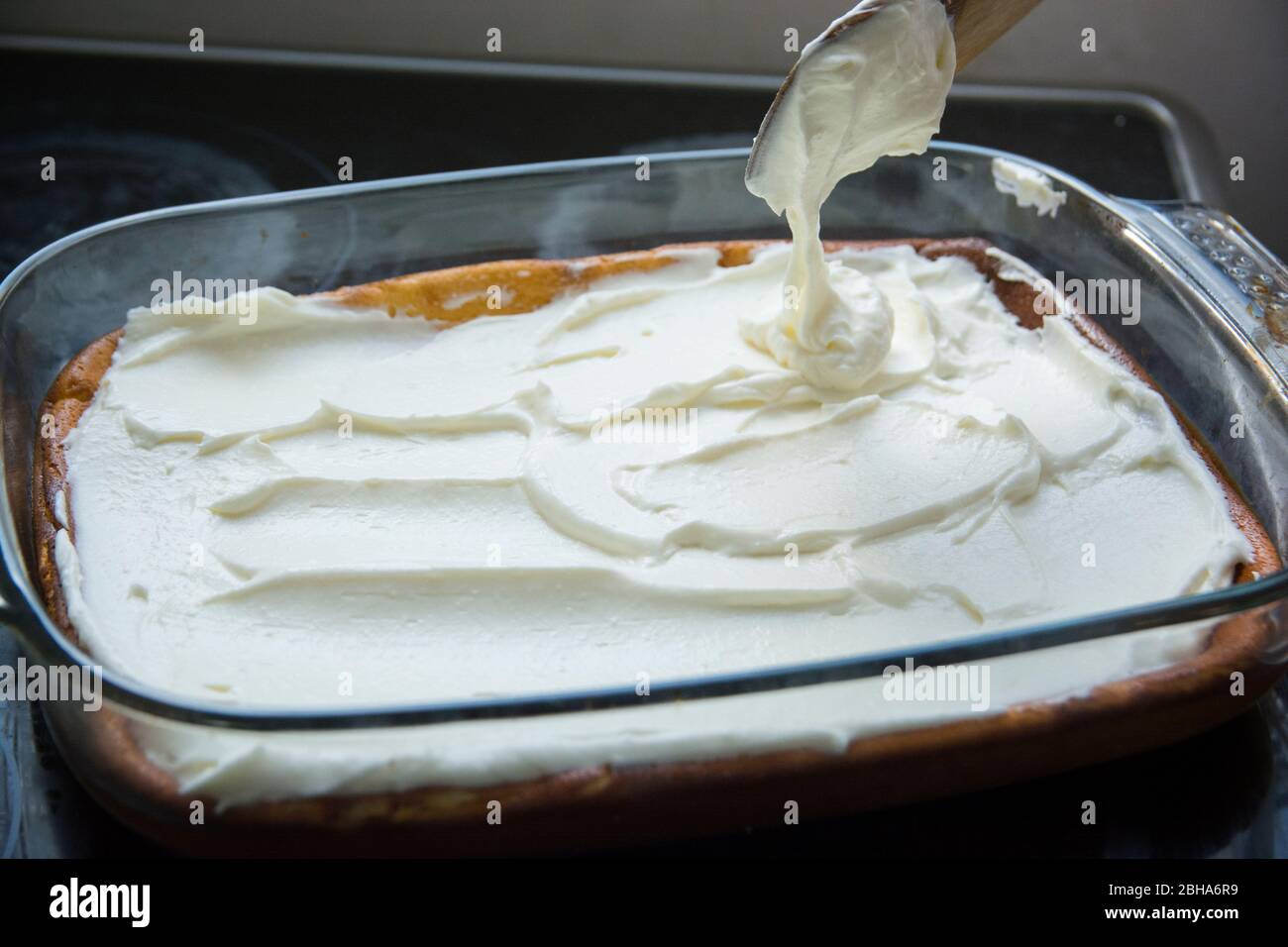 Applicare uno strato di panna montata su una torta di formaggio al forno Foto Stock