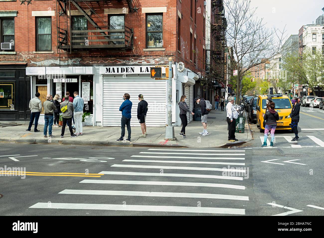Persone in attesa di prendere le bevande per andare a Maiden Lane, nell'East Village di New York City, durante la pandemia di coronavirus COVID 19 nell'aprile 2020. Foto Stock