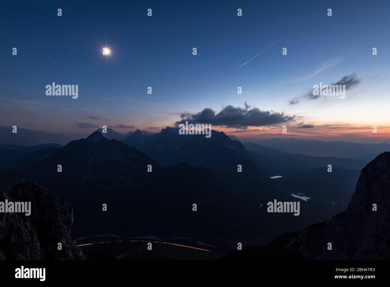 Wettersteingebirge e Wetterertspitze dal Karwendel fotografato di notte. In alto a sinistra la luna con raggi di luce. Foto Stock