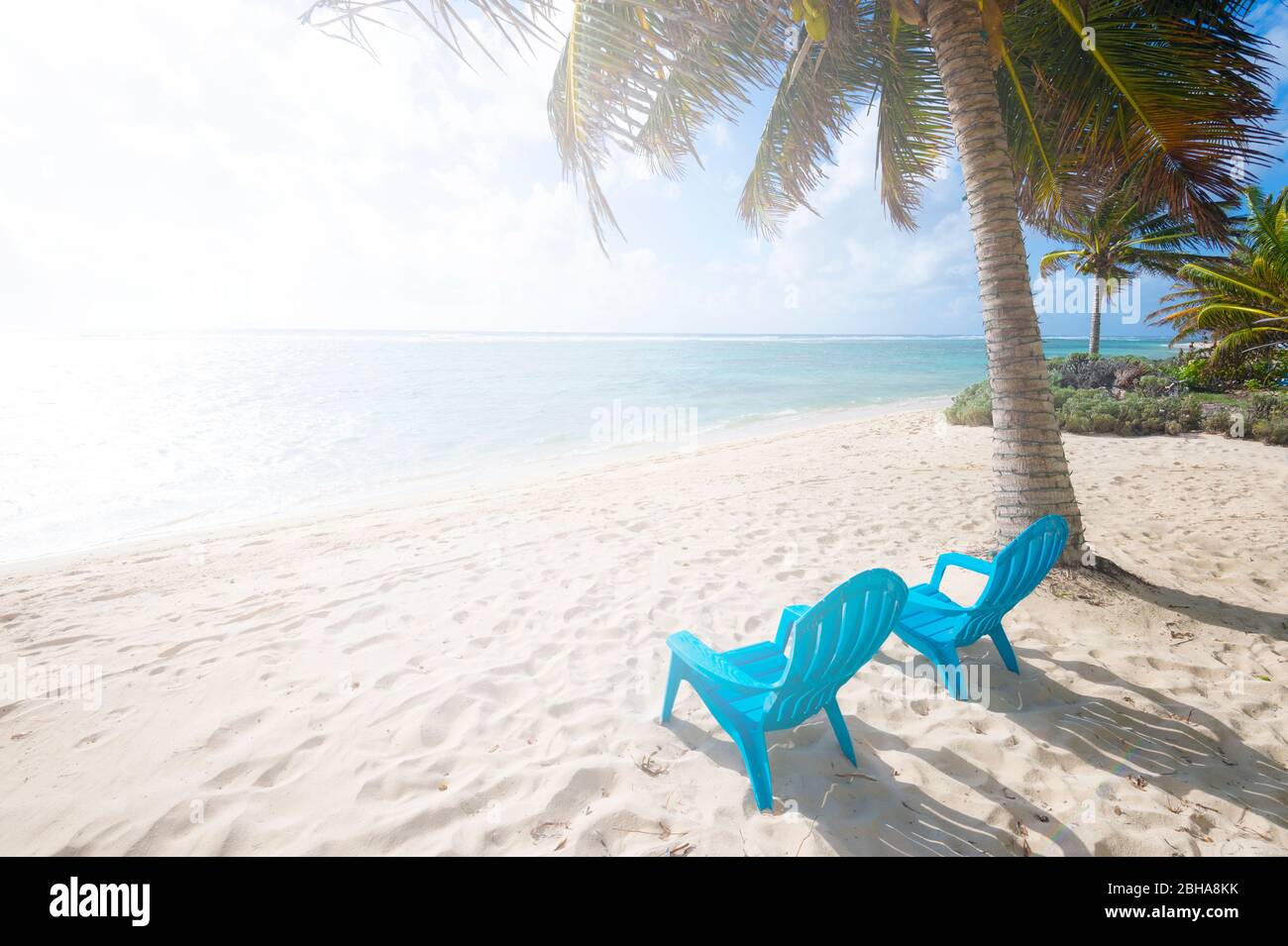 Due sedie da spiaggia con palme e un'atmosfera luminosa dal sole, Grand Cayman Island Foto Stock