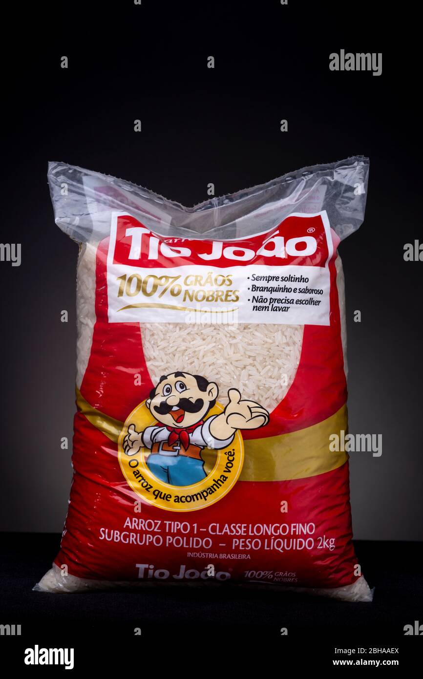 Foto in studio verticale con chiave bassa di un grande pacco da 2 kg di riso brasiliano bianco da cucina del marchio Tio João su sfondo grigio scuro Foto Stock