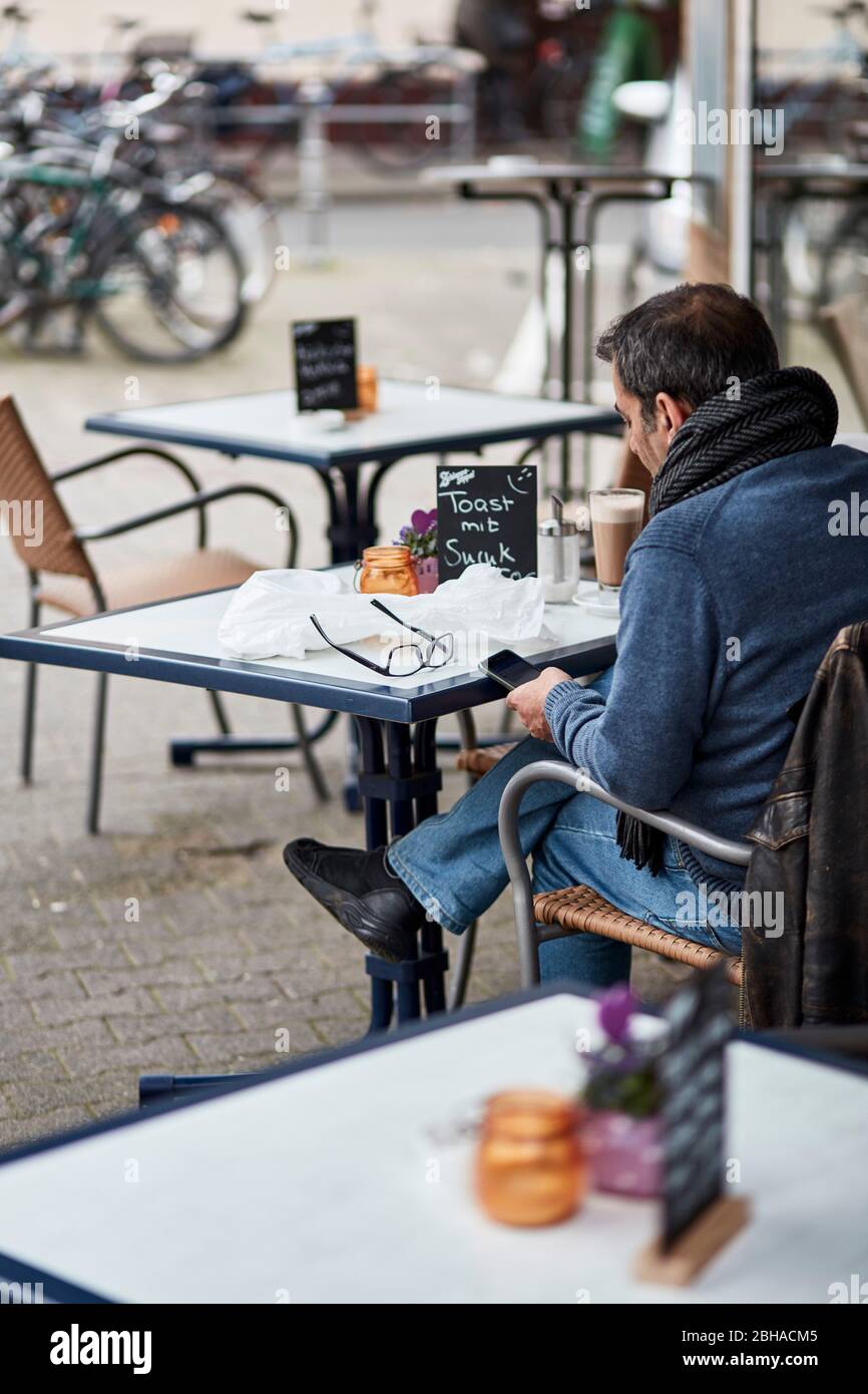 Europa, Deutschland, Hessen, Francoforte, Bornheim, Mann mit smartphone in einem Straßencafé Foto Stock