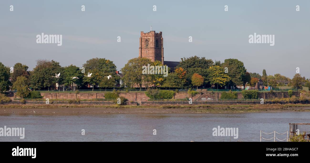 Chiesa di Santa Maria e un volo di cigni a Widnes visto attraverso l'estuario del Mersey dal traghetto Mersey in una crociera lungo il canale delle navi di Manchester Foto Stock