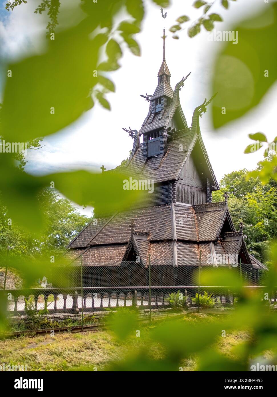 Storica chiesa a doghe in legno Fantoft guardando attraverso le foglie di un albero, Fantoftvegen Paradis, Hordaland, Norvegia, Scandinavia, Europa Foto Stock