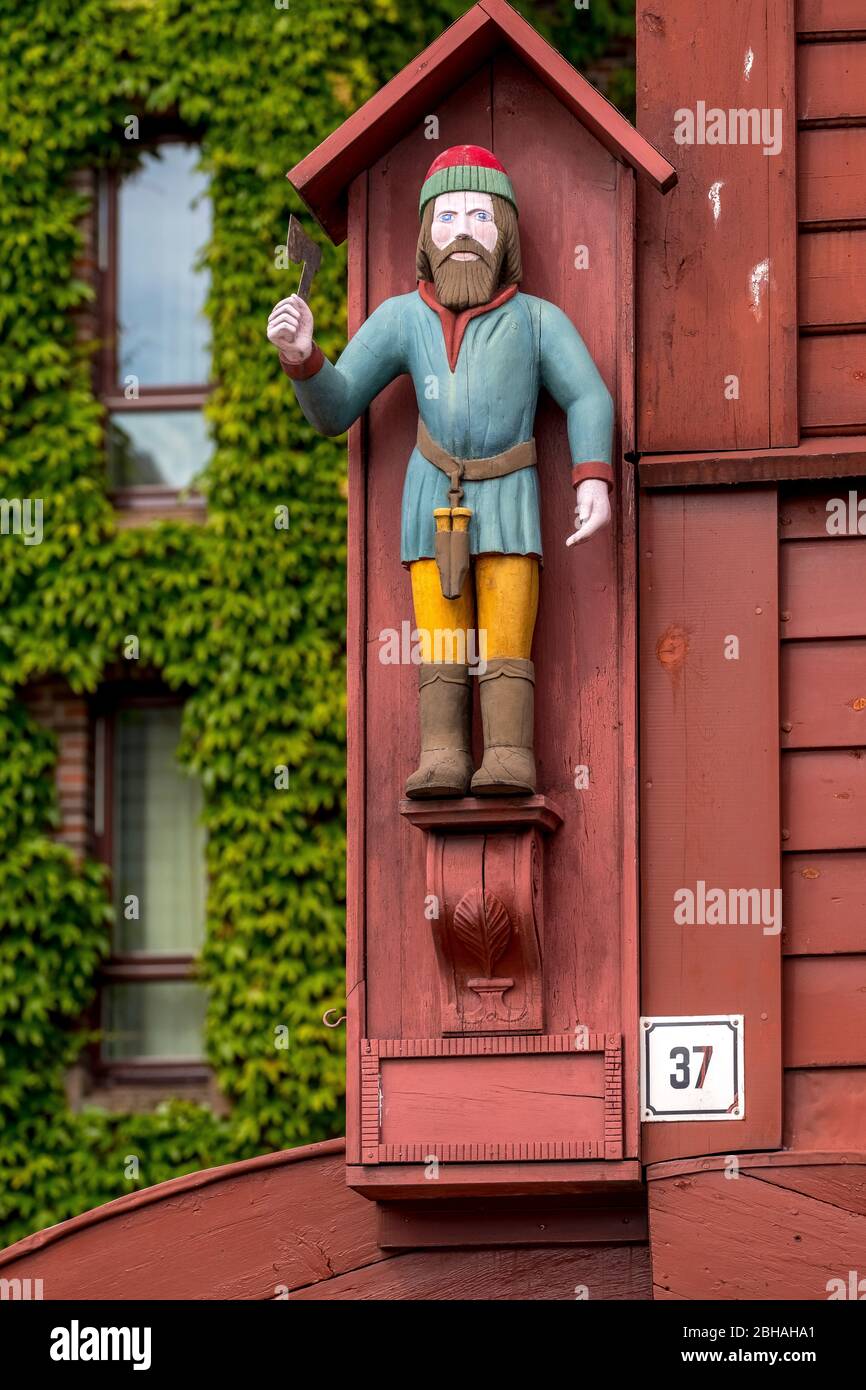 Personaggio colorato in legno di un uomo con un cappello a punta rossa sul muro di una storica casa in legno nel quartiere anseatico di Bryggen, Torget, il Molo Tedesco, Bergen, Hordaland, Norvegia, Scandinavia, Europa Foto Stock