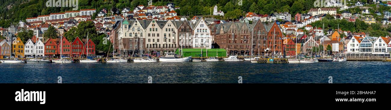 Nordsee, dietro una colorata case di legno fronte con barche a vela allegata nel porto di Bryggen, dietro di esso ulteriori case del posto sopra complessi alberghieri e foreste coperte di montagne, montagne, Hordaland, Norvegia, Scandinavia, Europa Foto Stock