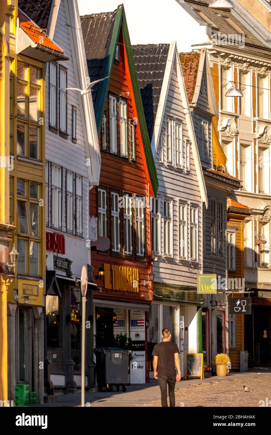 I turisti camminano nel quartiere portuale di Bryggen di fronte a un imponente case in legno, con negozi, montagne, Hordaland, Norvegia, Scandinavia, Europa Foto Stock